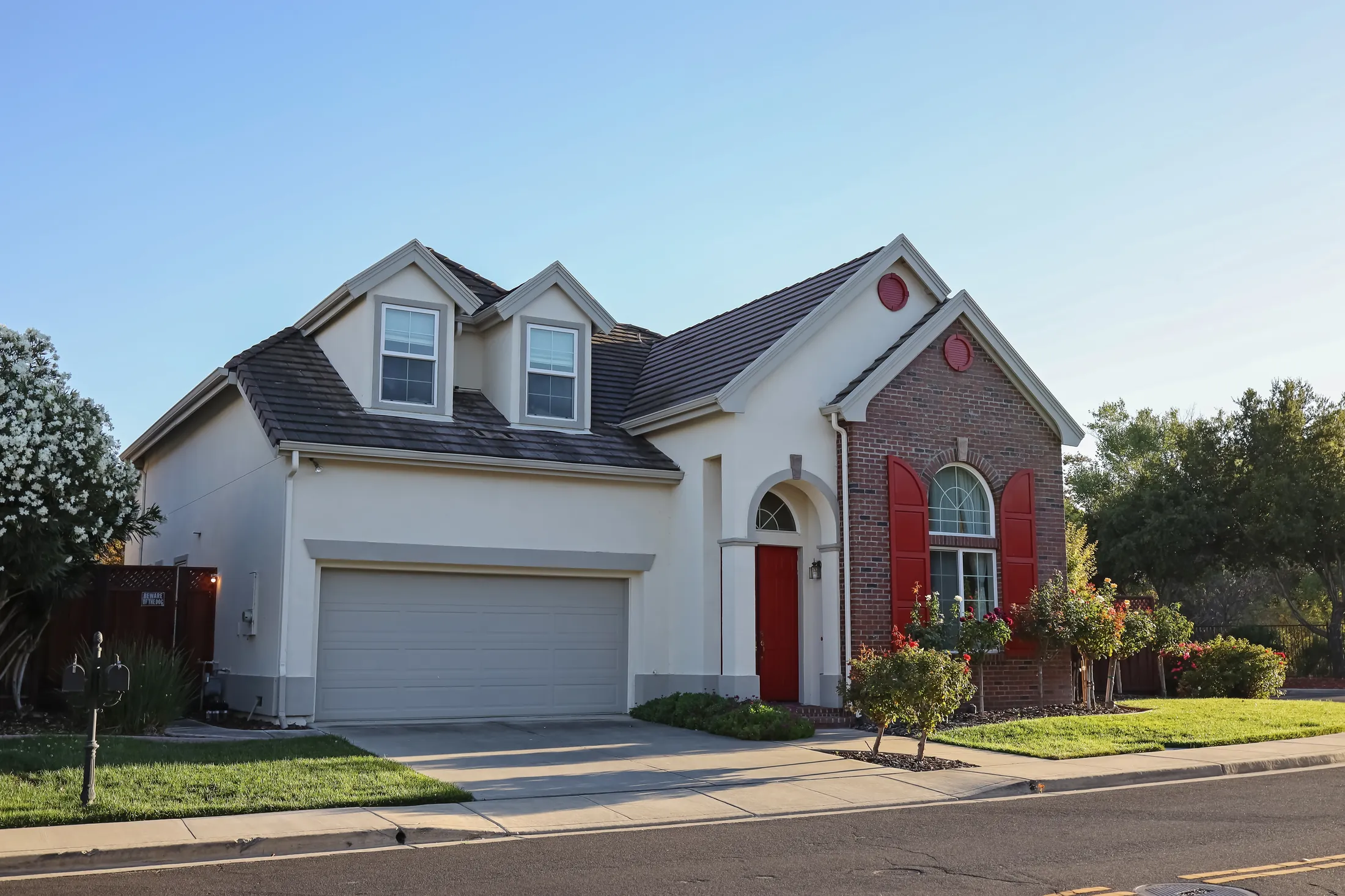 Two-story suburban home with a red front door and brick accents